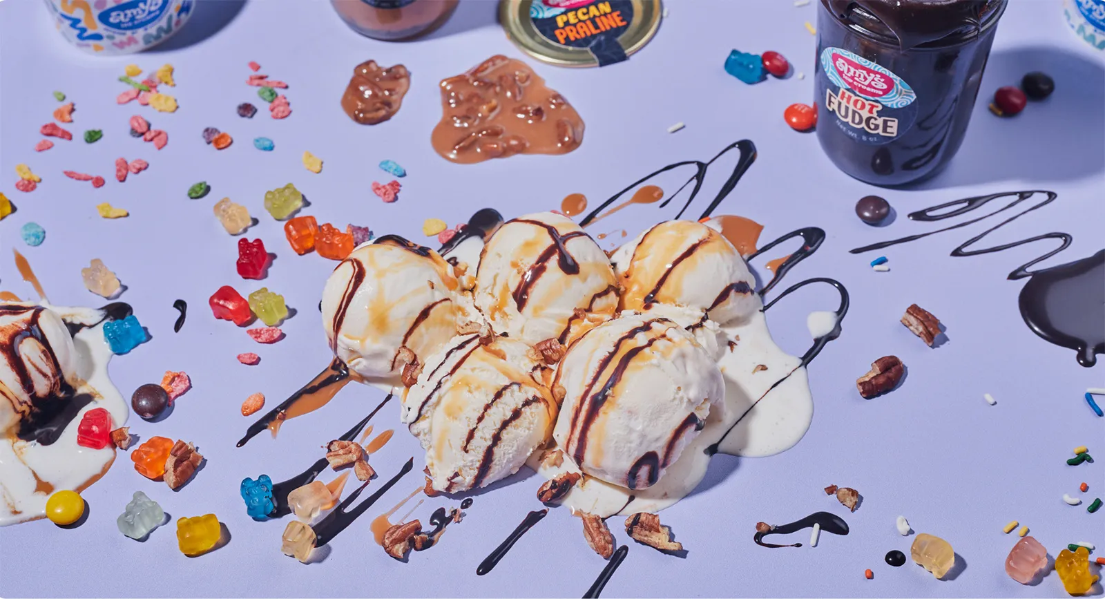 Image of ice cream, and toppings, and mixins on a purple table top